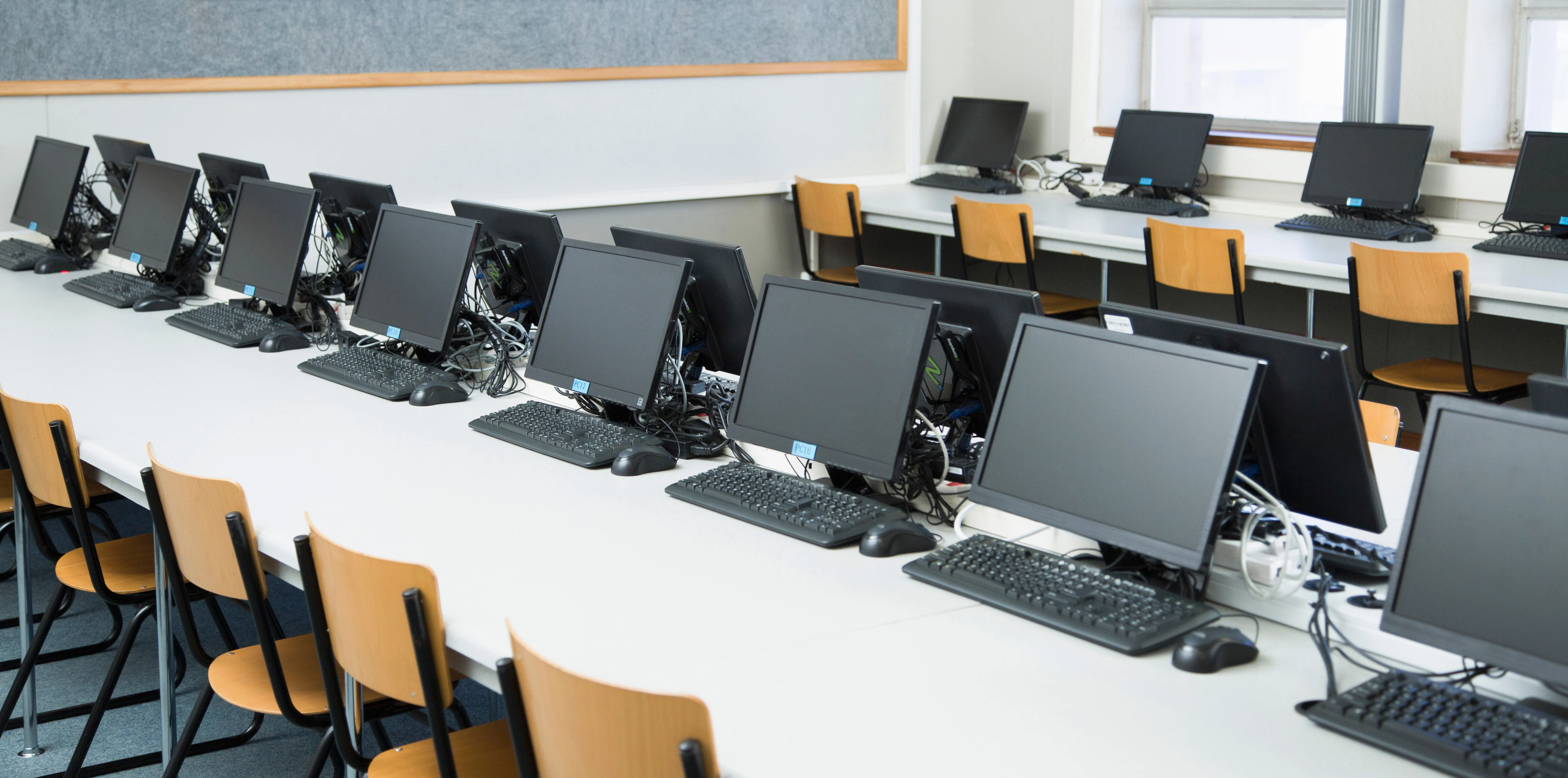 Laboratório de informática equipado com computadores para atividades educacionais, ilustrando a importância da infraestrutura tecnológica no acesso à educação digital e no desenvolvimento de competências dos estudantes.